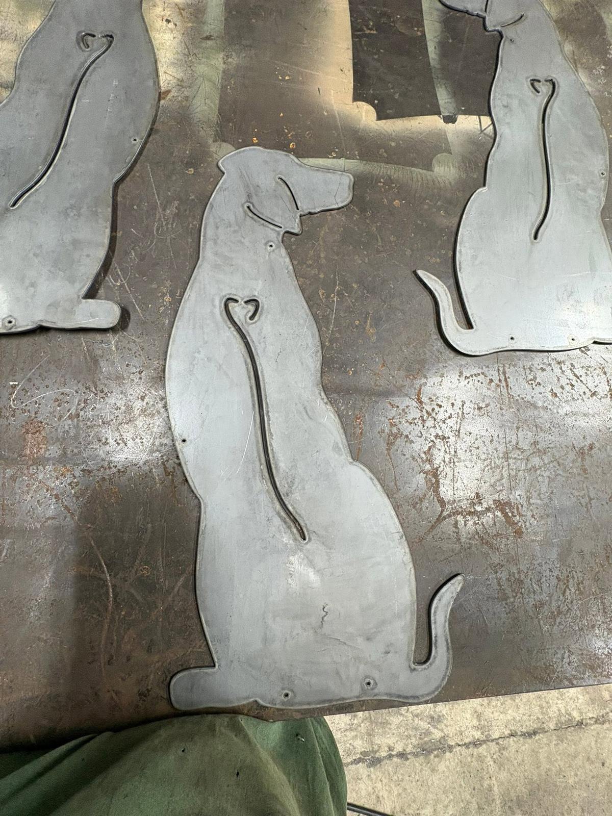 Steel dog-silhouette cutouts with heart cutouts, fresh off the plasma table