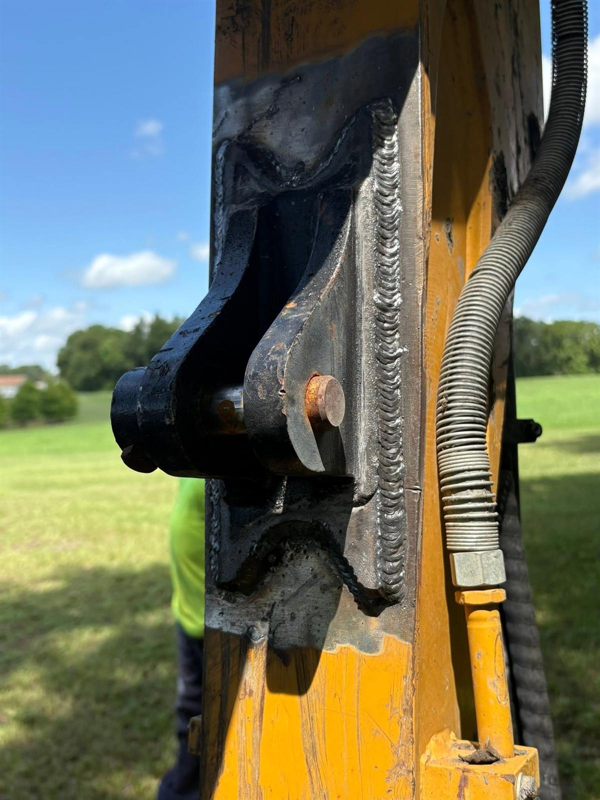 Fresh weld repair on the arm of a yellow excavator, done in the field